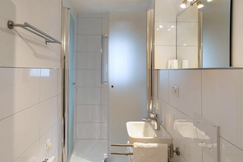 a white bathroom with a sink and a shower at Heikes Ferienwohnung in Schauenburg