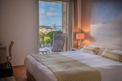 a bedroom with a bed and a large window at Hôtel Funtana Marina in LʼÎle-Rousse