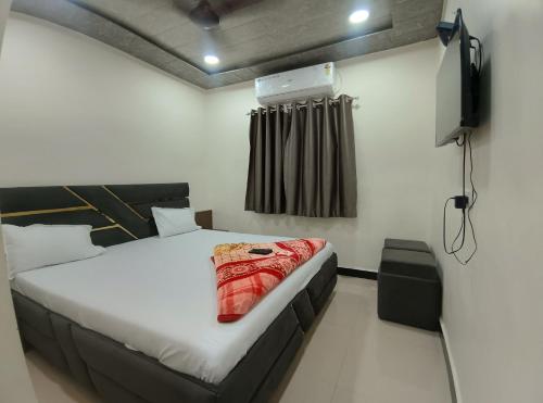 a bedroom with a bed and a television in it at Hotel Shree Balaji in Ujjain