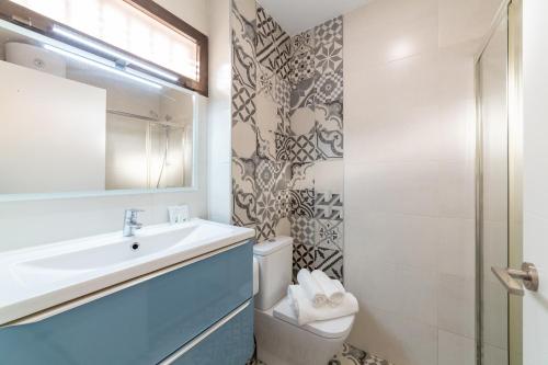 Un baño con lavabo, inodoro y espejo. en Las Buganvillas, en Roquetas de Mar