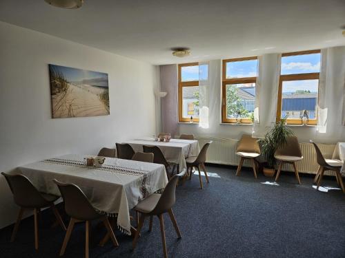 a room with two tables and chairs and windows at Hotel Garni in Rodewisch