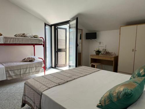a bedroom with two beds and a desk with a window at Hotel Abay in Rimini
