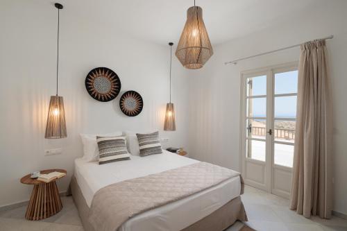 a white bedroom with a bed and a window at Evdokia - Luxury Olive Yard apartment with Aegean View in Moutsouna Naxos