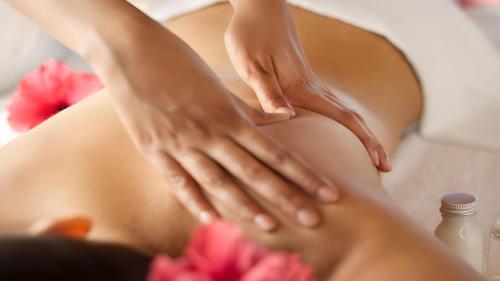 a woman getting a massage in a massage table with flowers at Villa Kaniksa in Candidasa