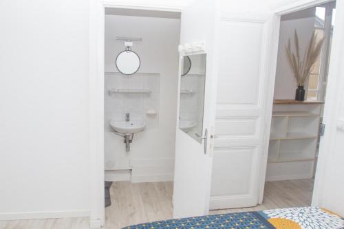 une salle de bain blanche avec un lavabo et un miroir dans l'établissement All shops available by foot, à Nantes