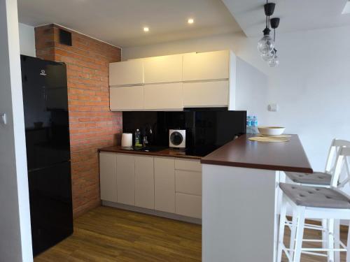 a kitchen with white cabinets and a brick wall at Downtown Apartment in Warsaw