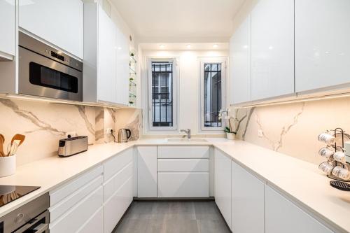 une cuisine blanche avec des armoires blanches et un évier dans l'établissement GuestReady - Bel apt proche du Louvre, à Paris