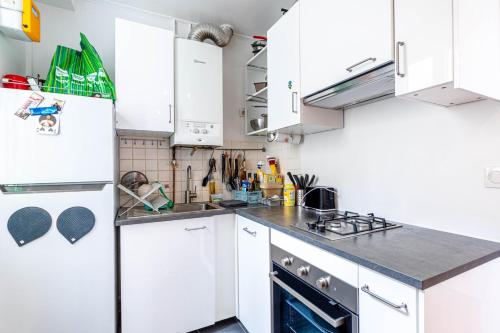 une cuisine avec des armoires blanches et un four à plaques de cuisson dans l'établissement GuestReady - Bright stay next to The Eiffel Tower, à Paris