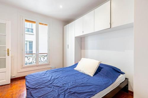 une chambre avec un lit avec des draps bleus et une fenêtre dans l'établissement GuestReady - Bright stay next to The Eiffel Tower, à Paris