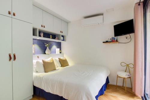 - une chambre avec un lit blanc et une télévision murale dans l'établissement GuestReady - Lovely family retreat near The Louvre, à Paris