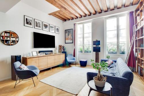 un salon avec un canapé bleu et une télévision dans l'établissement GuestReady - Lovely family retreat near The Louvre, à Paris