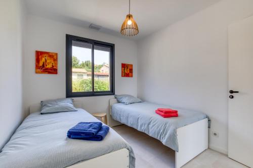 deux lits dans une chambre avec une fenêtre dans l'établissement Villa Maryet, à Sommières