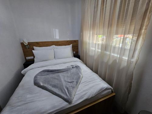 a bed with a blanket on it next to a window at Hostel PREMIUM in Derventa
