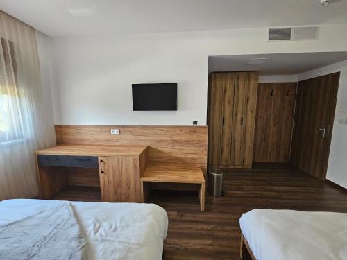 a hotel room with a desk and a tv on a wall at Hostel PREMIUM in Derventa