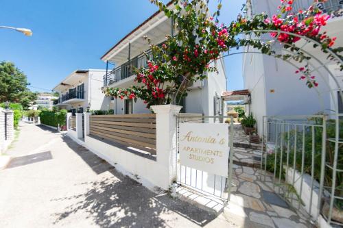 a building with a gate with a sign and flowers at Antonia's Apartments in Kassiopi