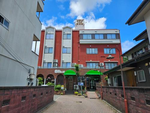 a tall red brick building with green umbrellas at Plaza Inn Kawaguchiko in Fujikawaguchiko