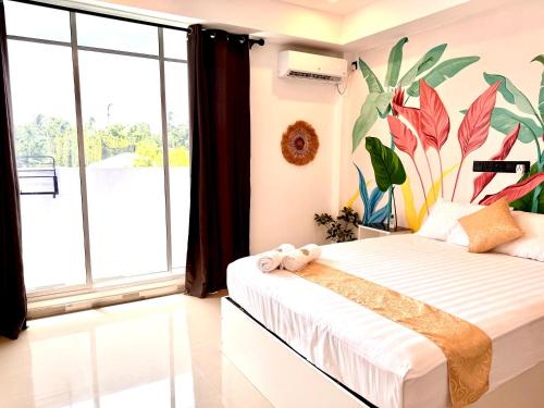 a bedroom with a bed with a tropical mural on the wall at Sands Garden Hotel in Thoddoo