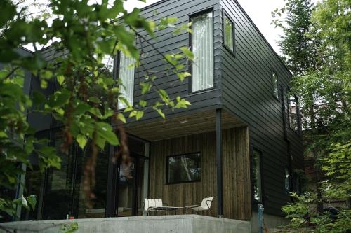 a house with black siding and a porch at 山郷 Villas in Nature in Otaru