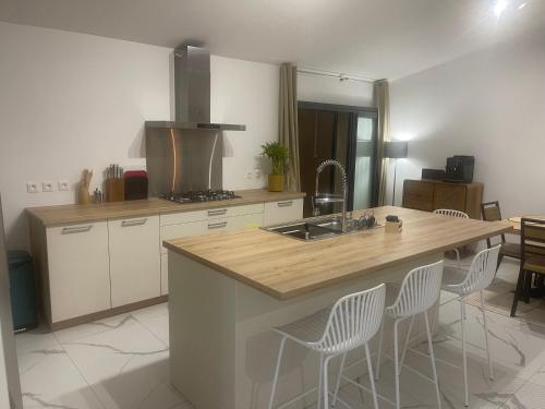 a kitchen with a sink and a counter with chairs at Le Jacquier Life House in Saint-Pierre