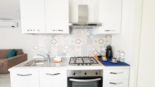 a white kitchen with a stove and a sink at Orchidea & Ortensia by Ca-Sa Check in Chioggia