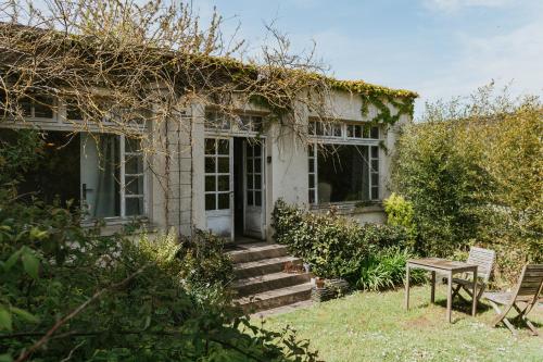 une maison blanche avec une table et une chaise dans l'établissement Appartement les Glycines - Accès Piscine, à Criel-sur-Mer