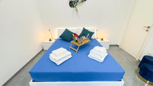 a blue bed with pillows and a table with towels at Orchidea & Ortensia by Ca-Sa Check in Chioggia