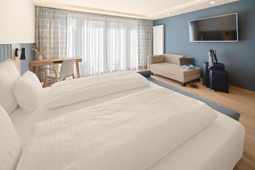 a bedroom with a large white bed and a living room at Hotel Dreiflüssehof in Passau