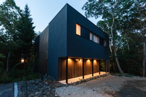 a black house in the middle of the forest at 山郷 Villas in Nature in Otaru