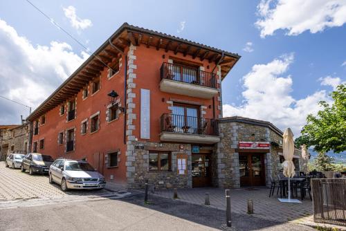 a red building with cars parked in front of it at Aparthotel Bellver in Bellver de Cerdanya 