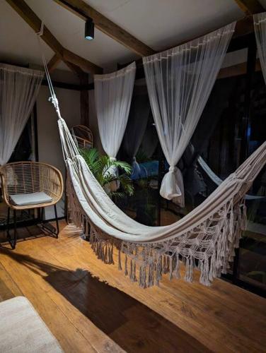 a hammock in a room with curtains and a chair at Balai Dulilit Entire Vacation Home with Free All Terrain Vehicle in El Nido