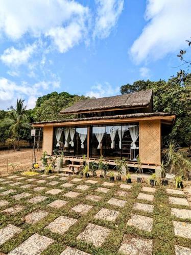 a small house with a roof on top of a yard at Balai Dulilit Entire Vacation Home with Free All Terrain Vehicle in El Nido