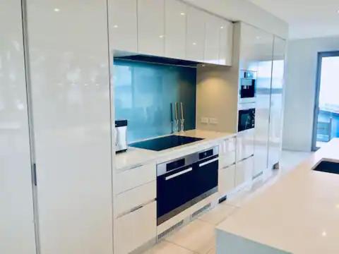 a kitchen with white cabinets and a blue sink at The perfect stop over in Wellington