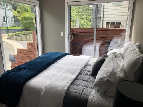 a bed in a bedroom with a large window at The perfect stop over in Wellington