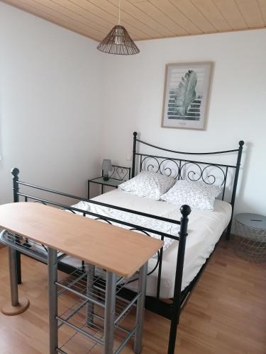 - une chambre avec un lit noir et une table en bois dans l'établissement Pays Basque loue appartement F3, à Ahetze