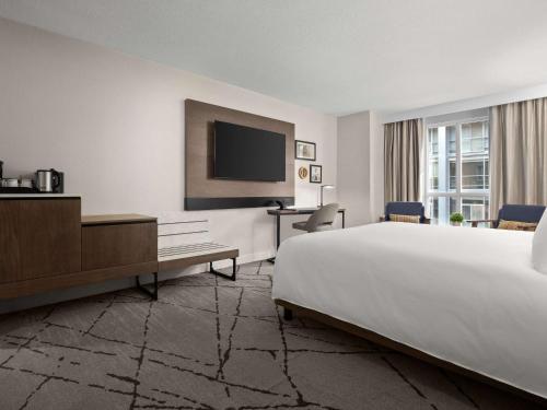 a hotel room with a bed and a flat screen tv at The Novotel Toronto Centre in Toronto