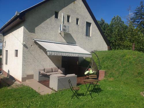 a building with an awning with a couch and chairs at Happy Family House Velence in Velence