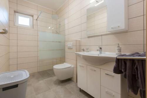 a white bathroom with a toilet and a sink at Villa Xenia A energy efficient in Labin