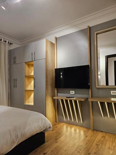 a bedroom with a bed and a flat screen tv at Cozy Homes in Cairo