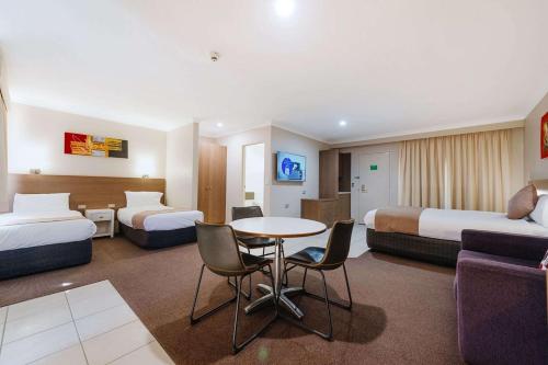 a hotel room with two beds and a table and chairs at Quality Hotel City Centre in Coffs Harbour