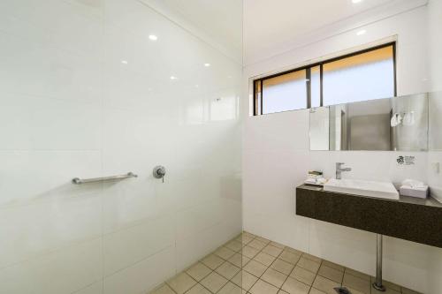 uma casa de banho branca com um lavatório e um espelho em Quality Hotel City Centre em Coffs Harbour