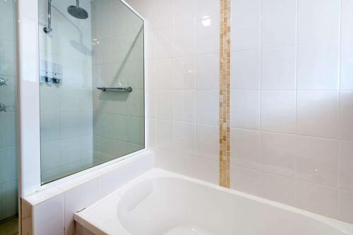a white bathroom with a tub and a shower at Quality Hotel City Centre in Coffs Harbour