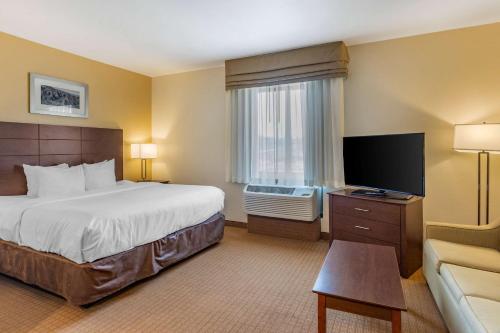 a hotel room with a bed and a flat screen tv at MainStay Suites Near Denver Downtown in Denver