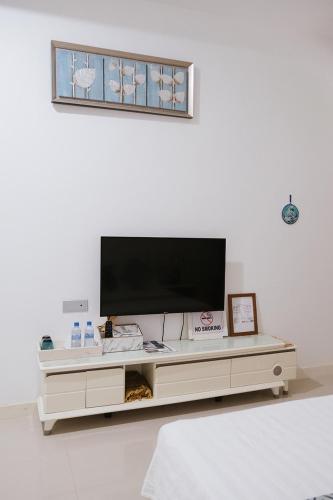 a living room with a tv on a white wall at Fiyala Homestay in Feydhoo