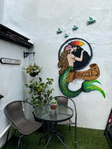 a table and chairs in front of a wall at SNUGGLES in Weymouth
