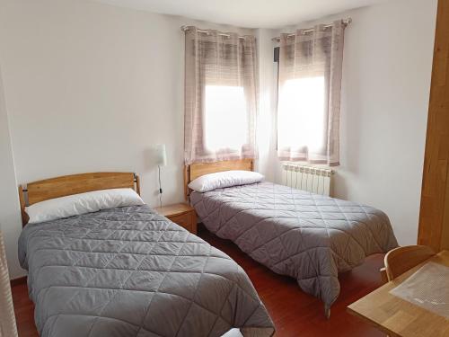 zwei Betten in einem Zimmer mit zwei Fenstern in der Unterkunft Casa en Granada zona residencial El Serrallo in Granada