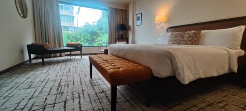 a hotel room with a bed and a chair and a window at Hotel Marine Plaza in Mumbai