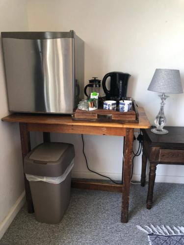 a television sitting on a wooden table with a trash can at Ollava Guesthouse in Simonʼs Town