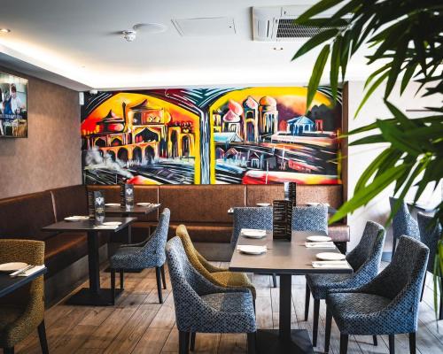 a restaurant with tables and chairs and a painting on the wall at DeiRa Hotel & Apartments in Prestwick