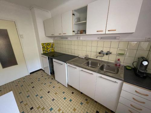 une cuisine avec des armoires blanches et un évier dans l'établissement wonderland appart tout équipé, à Strasbourg