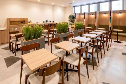 a restaurant with tables and chairs and plants at Comfort Hotel Matsuyama in Matsuyama
